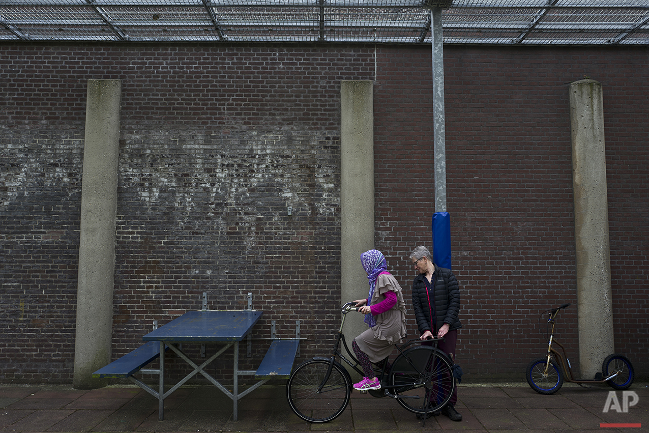  In this Monday, May 2, 2016 photo, a Dutch volunteer teaches an Afghan refugee woman how to ride a bicycle at a yard in the former prison of De Koepel in Haarlem, Netherlands. (AP Photo/Muhammed Muheisen) 