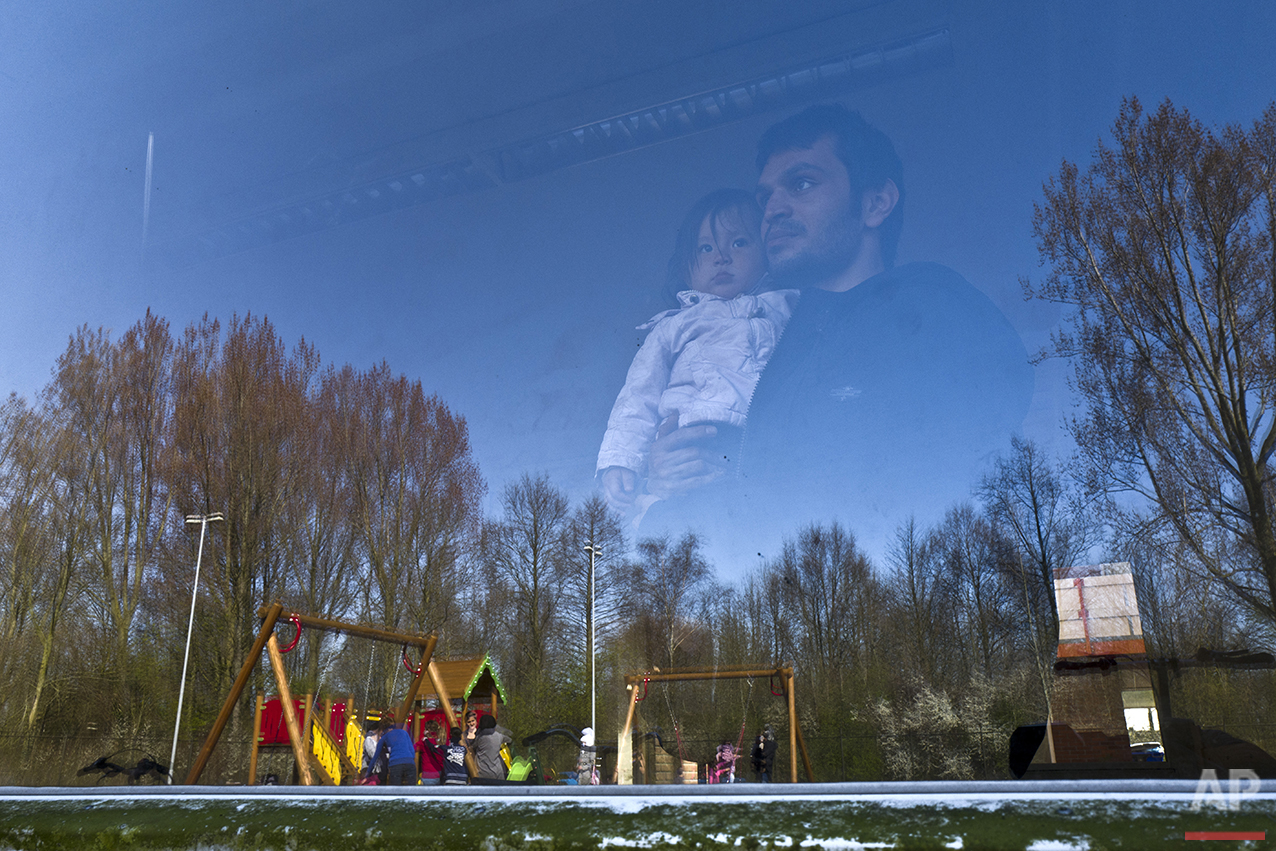  In this Sunday, April 10, 2016 photo, an Afghan refugee holding a child looks outside a window of a room at the former prison of Westlingen in Heerhugowaard northwestern Netherlands. (AP Photo/Muhammed Muheisen) 