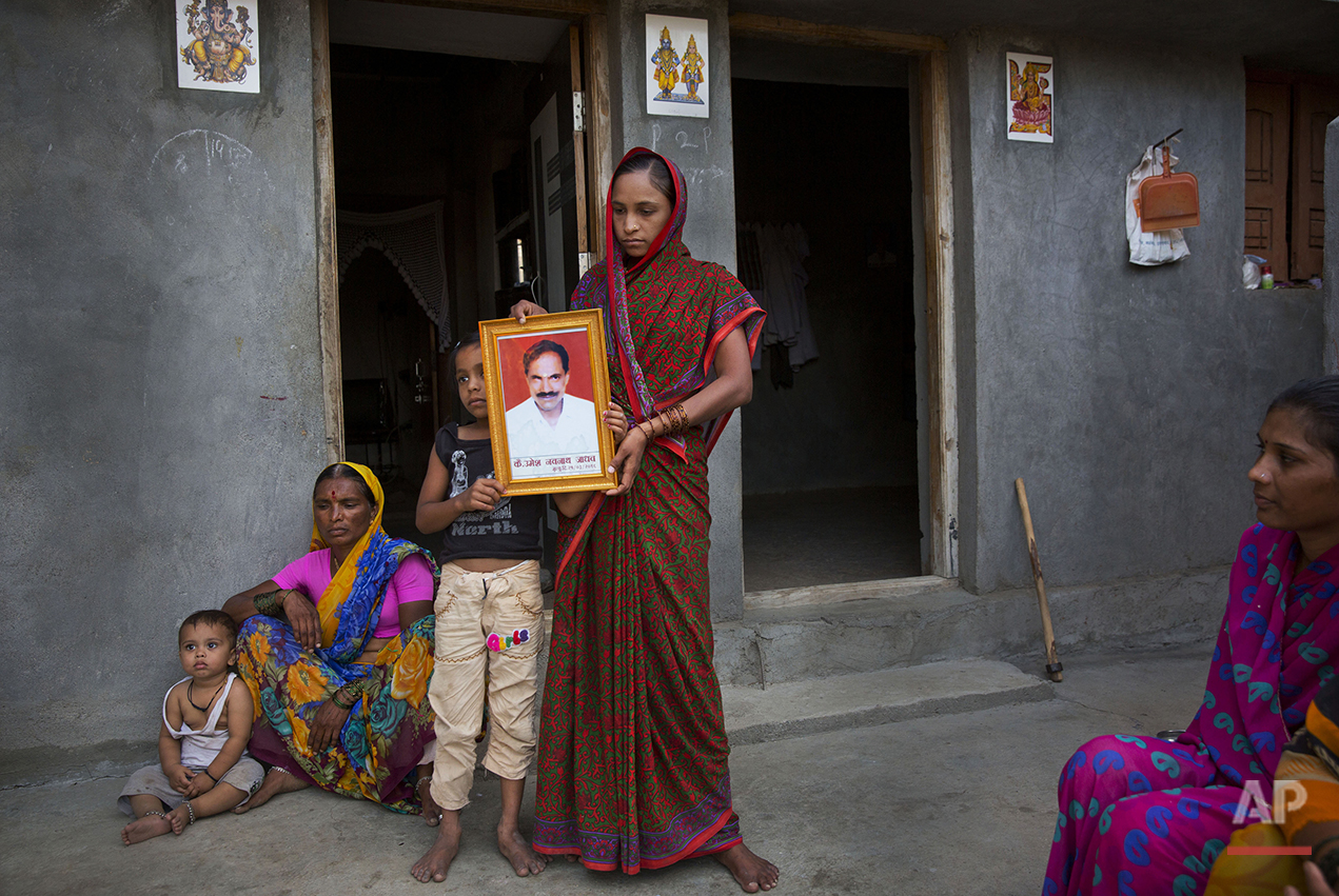  In this May 10, 2016, photo, Rajana Umesh Jadav, 30, center, with her daughter Shruti, 10, and son Shitij, 4, left, shows the portrait of her husband Umesh Navnath Jadav, who fell into a well while fetching water at a village on the outskirts of Lat