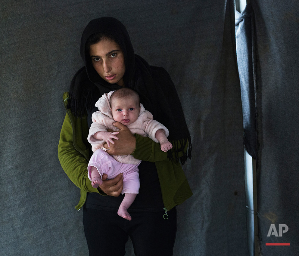   In this picture made on Thursday, May 12, 2016, 17-years-old Soumaya Zallaan, a Syrian mother from the city of Deir ez-Zor , poses with her baby girl Ritag in a tent made of blankets given by the UNCHR at the refugee camp of the northern Greek bord