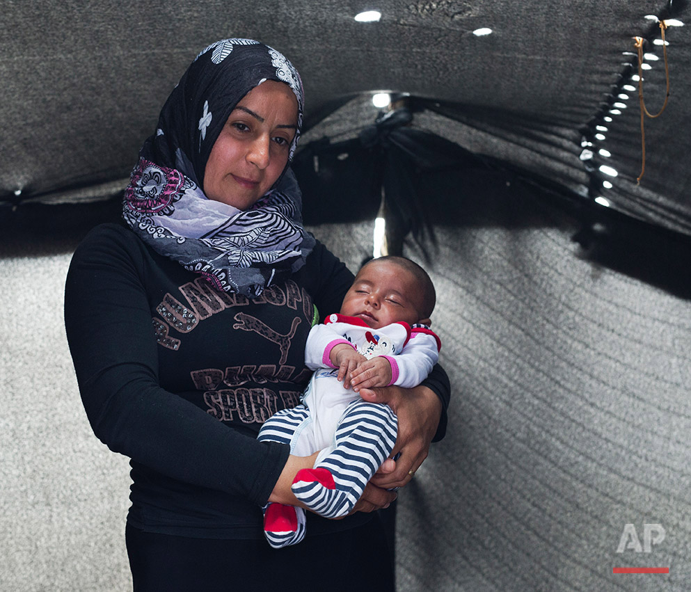   In this picture made on Thursday, May 12, 2016, 30-years-old Roula Al Shihabi a Syrian mother from the city of Alepo poses with her baby boy Abu Bark  in a tent made of blankets given by the UNCHR at the refugee camp of the northern Greek border po