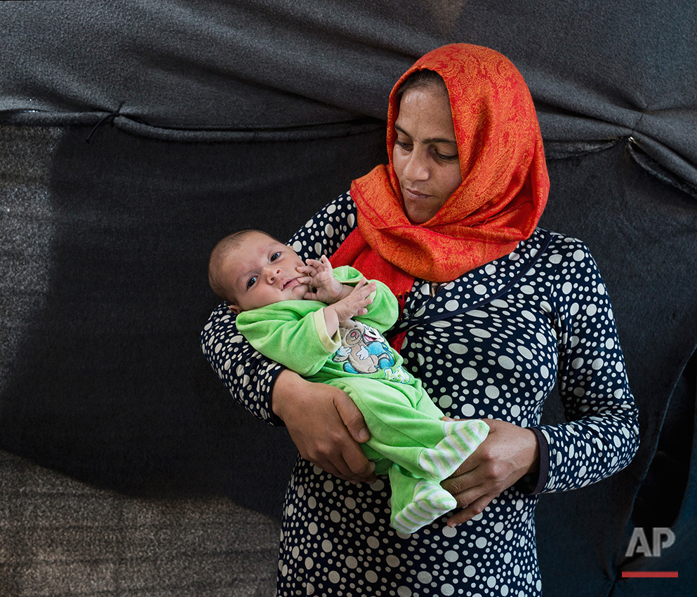   In this picture made on Sunday, May 15, 2016, 34- years-old Wajdan Shalhob a Syrian woman from Daraa city poses with her baby boy Faouaz in a tent made of blankets given by the UNCHR at the refugee camp of the northern Greek border point of Idomeni