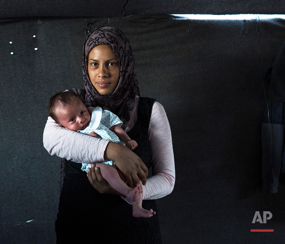   In this picture made on Thursday, May 12, 2016, 19-year-old Rajad Alhelo, a Syrian mother from the city of Deir ez-Zor poses with her baby girl Yasmin in a tent made of blankets given by the UNCHR at the refugee camp of the northern Greek border po
