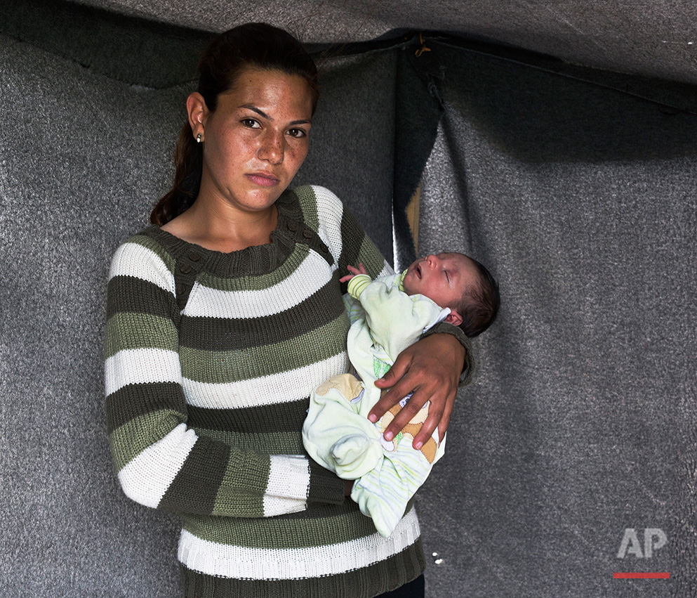   In this picture made on Sunday, May 15, 2016, 23-year-old Nariman, a Kurdish-Syrian mother from Kobani, poses with her baby boy Raman in a tent made of blankets given by the UNCHR at the refugee camp of the northern Greek border point of Idomeni. N