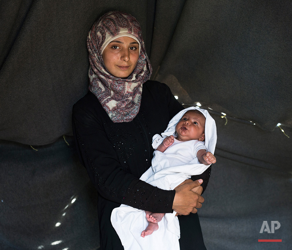   In this picture made on Saturday, May 14, 2016, 19-years-old Farah Sheikh Ahmed a Syrian mother from the city of Idlib poses with her baby girl Maram in a tent made of blankets given by the UNCHR at the refugee camp of the northern Greek border poi