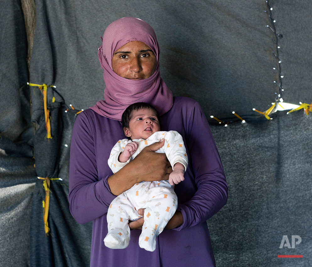  In this picture made on Sunday, May 15, 2016, 28-year-old Samar, a Syrian mother from the city of Deir ez-Zor , poses with her baby girl Sedan, in a tent made of blankets given by the UNCHR at the refugee camp of the northern Greek border point of I