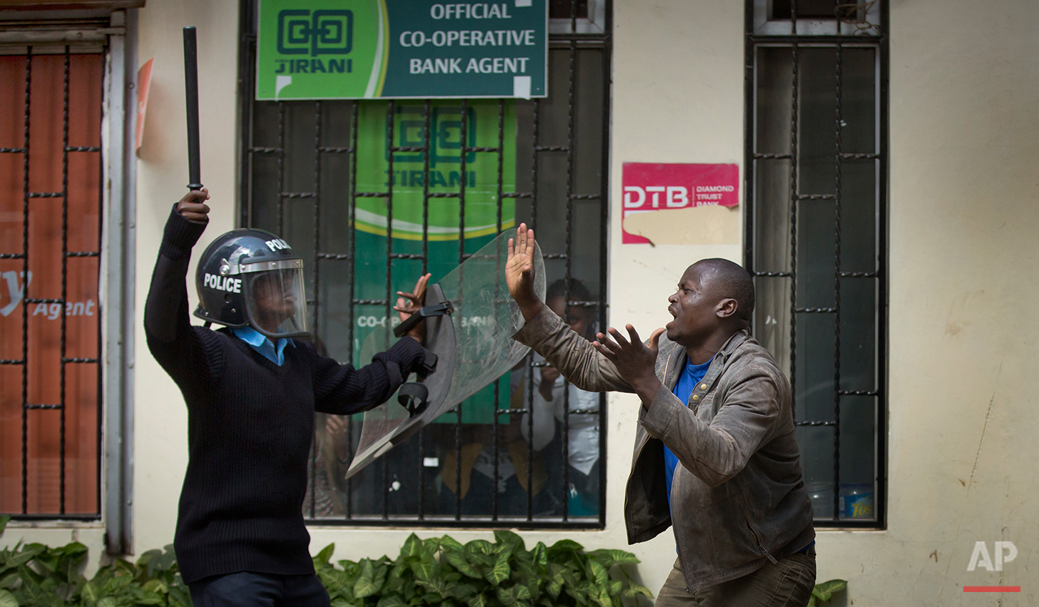 An opposition supporter pleads with a riot policeman, after being beaten with a wooden club by one then managing to escape but then being cornered by another, during a protest in downtown Nairobi, Kenya Monday, May 16, 2016. Kenyan police have tear-