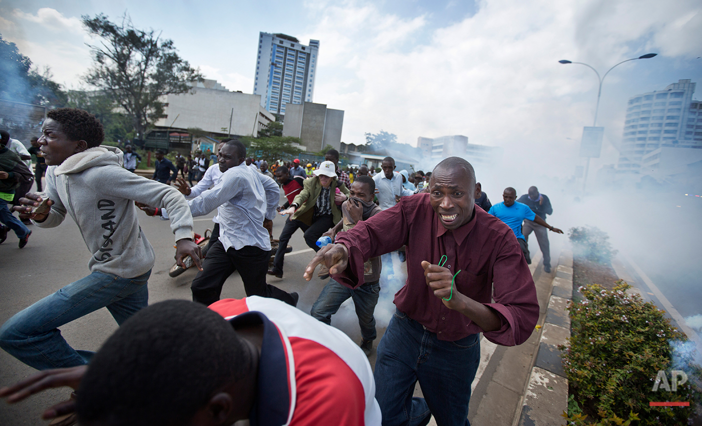  Opposition supporters, some carrying rocks, flee from clouds of tear gas fired by riot police, during a protest in downtown Nairobi, Kenya Monday, May 16, 2016. Kenyan police have tear-gassed and beaten opposition supporters during a protest demandi