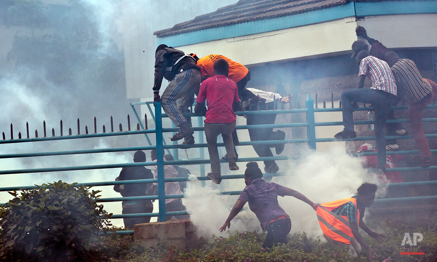  Opposition supporters climb over a fence into the University of Nairobi campus, as they flee from clouds of tear gas fired by riot police, during a protest in downtown Nairobi, Kenya Monday, May 16, 2016. Kenyan police have tear-gassed and beaten op
