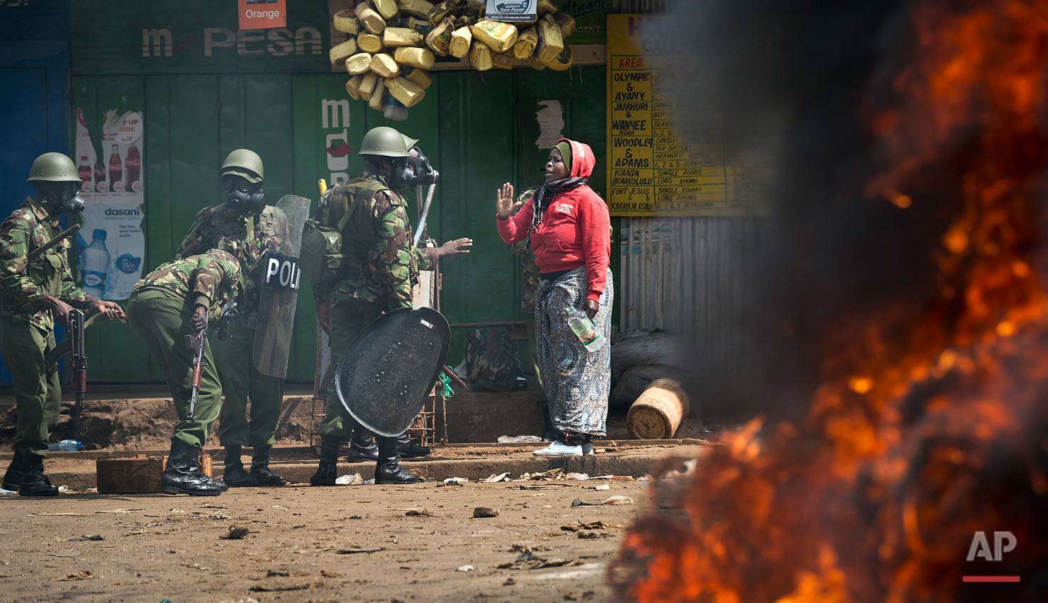  A woman resident talks with police as they engage in running battles between police firing tear gas and protesters throwing rocks, in the Kibera slum of Nairobi, Kenya Monday, May 23, 2016. Kenya's police shot, beat and tear gassed opposition demons