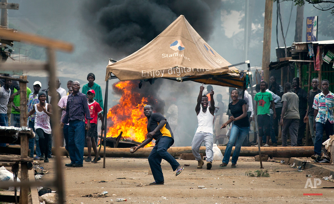  Opposition protesters throw rocks in front of barricades of burning tires, as they engage in running battles with police firing tear gas, in the Kibera slum of Nairobi, Kenya Monday, May 23, 2016. Kenya's police shot, beat and tear gassed opposition