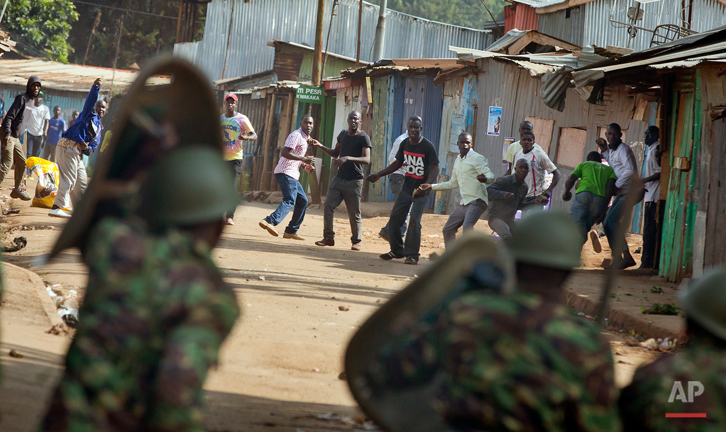  Opposition protesters throw rocks as they engage in running battles with police firing tear gas, in the Kibera slum of Nairobi, Kenya Monday, May 23, 2016. Kenya's police shot, beat and tear gassed opposition demonstrators across the country who tri