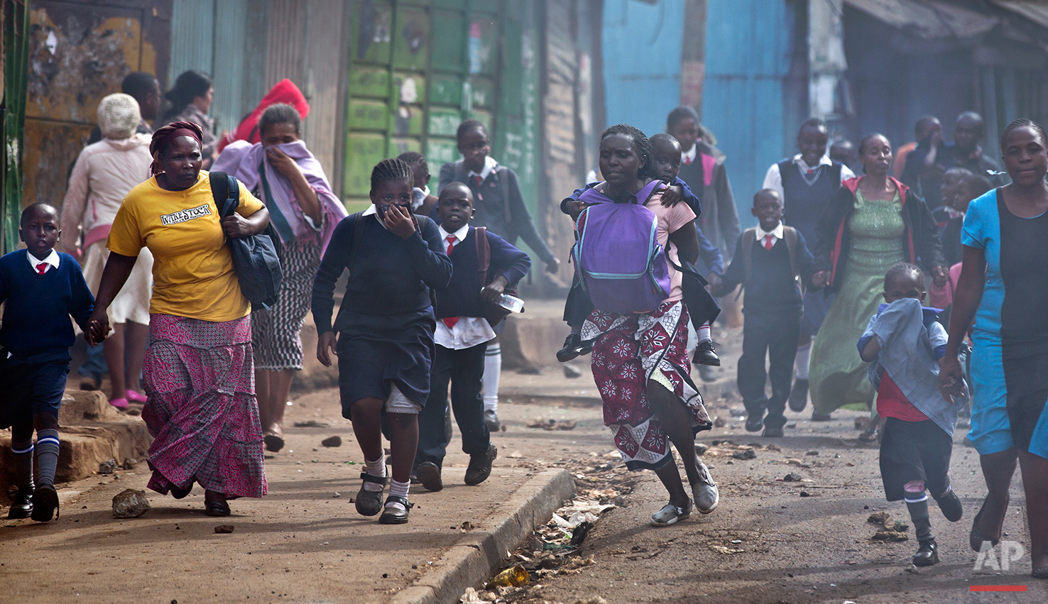 Women and schoolchildren take advantage of a lull in the clashes to run to safety, as police firing tear gas engage protesters throwing rocks in the Kibera slum of Nairobi, Kenya Monday, May 23, 2016. Kenya's police shot, beat and tear gassed opposi