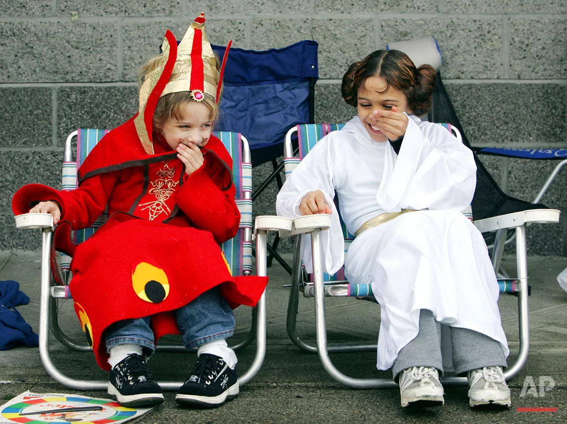 Aurora Olayos, left, 6, dressed as Queen Amidala, shares a laugh with sister Ariel Olayos, 9, right, dressed as Princess Leia, as they sit outside the Lloyd Cinemas waiting for the opening of "Star Wars: The Revenge of the Sith" in Portland, Ore., Wednesday, May 18, 2005. Both girls won tickets to the grand opening of the movie with their costumes. The movie opens nationwide, Thursday. (AP Photo/Don Ryan)