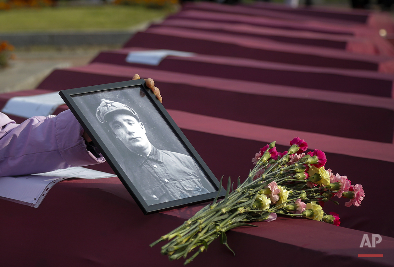  In this photo taken on Friday, Sept. 18, 2015, Zoya Izotova, niece of Ivan Shagichev, Soviet soldier killed in 1941, holds a portrait of her uncle at a coffin with his remains during a burial ceremony in a memorial cemetery at Nevsky Pyatachok near 