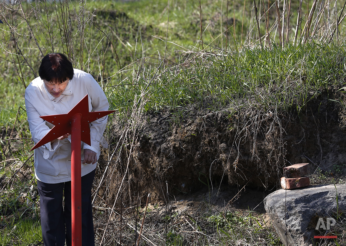  In this photo taken on Monday, May  2, 2016, a woman reads the names of Soviet soldiers whose remains were uncovered at the place and then reburied, at Nevsky Pyatachok near Kirovsk,  Russia. Nevsky Pyatachok, an area about 50 kilometers (30 miles) 