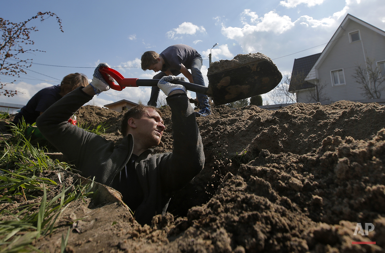  In this photo taken on Tuesday, May  3, 2016, members of a volunteer group searching for the remains of Soviet soldiers killed during WWII, dig to uncover remains of  Soviet soldiers at the yard of a private house at Nevsky Pyatachok near Kirovsk,  