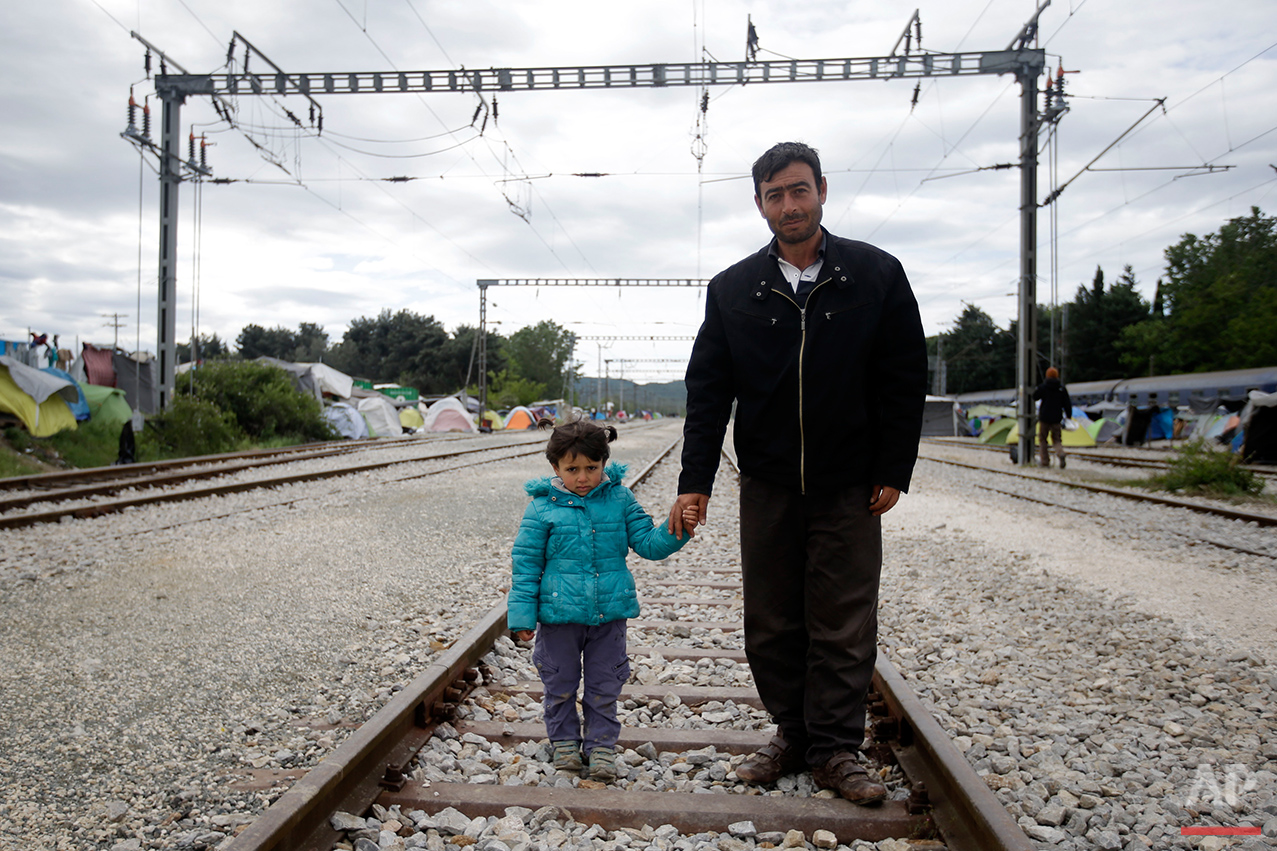  Adid Al Barum, right, holds the hand of his 4-year-old daughter Ala, as they pose for a portrait on the tracks of a rail way station which was turned into a makeshift camp crowded by migrants and refugees at the northern Greek border point of Idomen