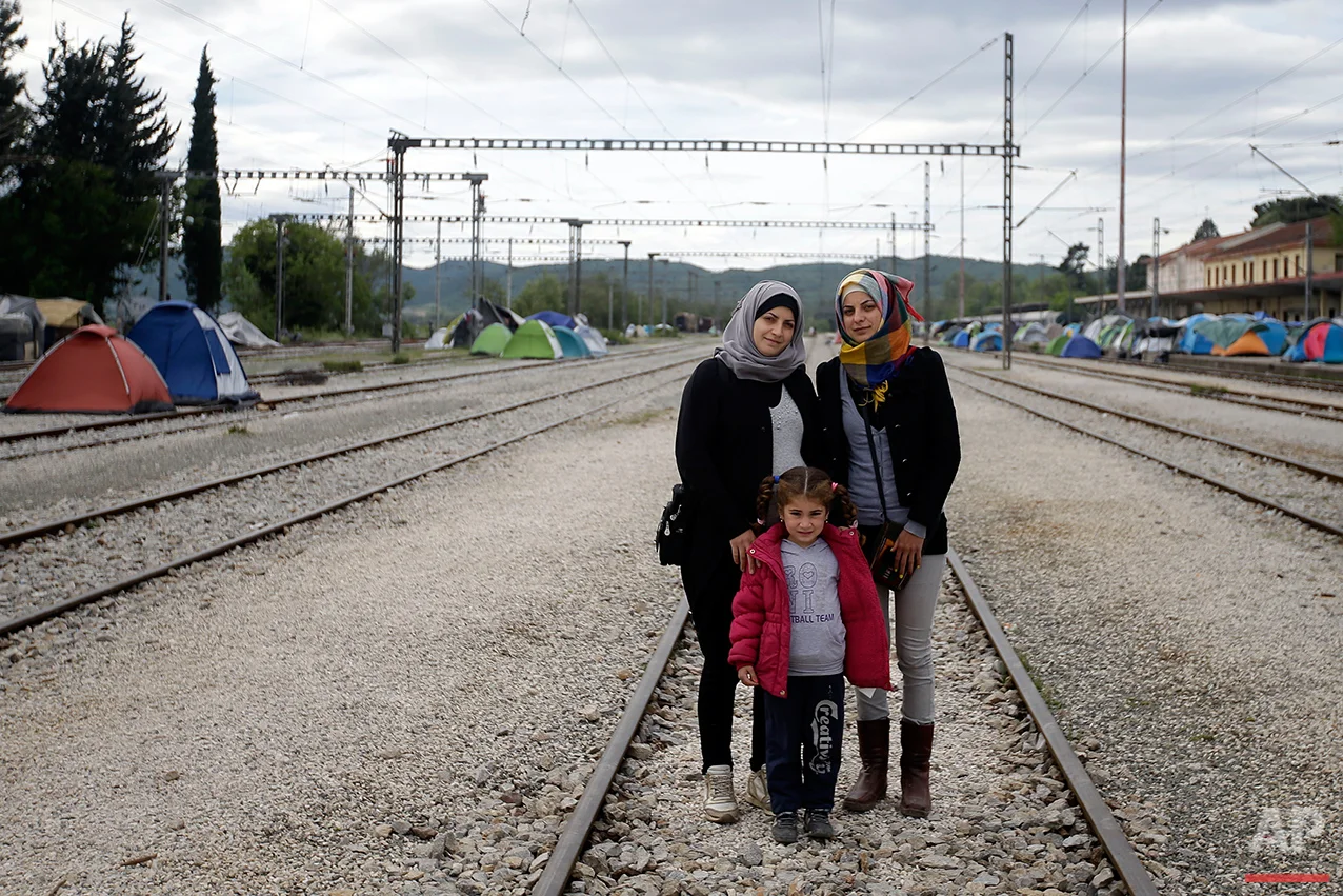 Syrian Magdolin Hameidi, left, poses for a portrait with her friend Juanin Ala, and her daughter Jana, 5 years old, on the tracks of a rail way station which was turned into a makeshift camp crowded by migrants and refugees at the northern Greek border point of Idomeni, Greece, Tuesday, May 3, 2016. At Greece’s blockaded border with Macedonia, 10,000 people who arrived hoping to start new lives farther west and north in Europe are settling instead into lives in limbo, sleeping in tents in mud and rain as they wait to find out what happens next. (AP Photo/Gregorio Borgia)