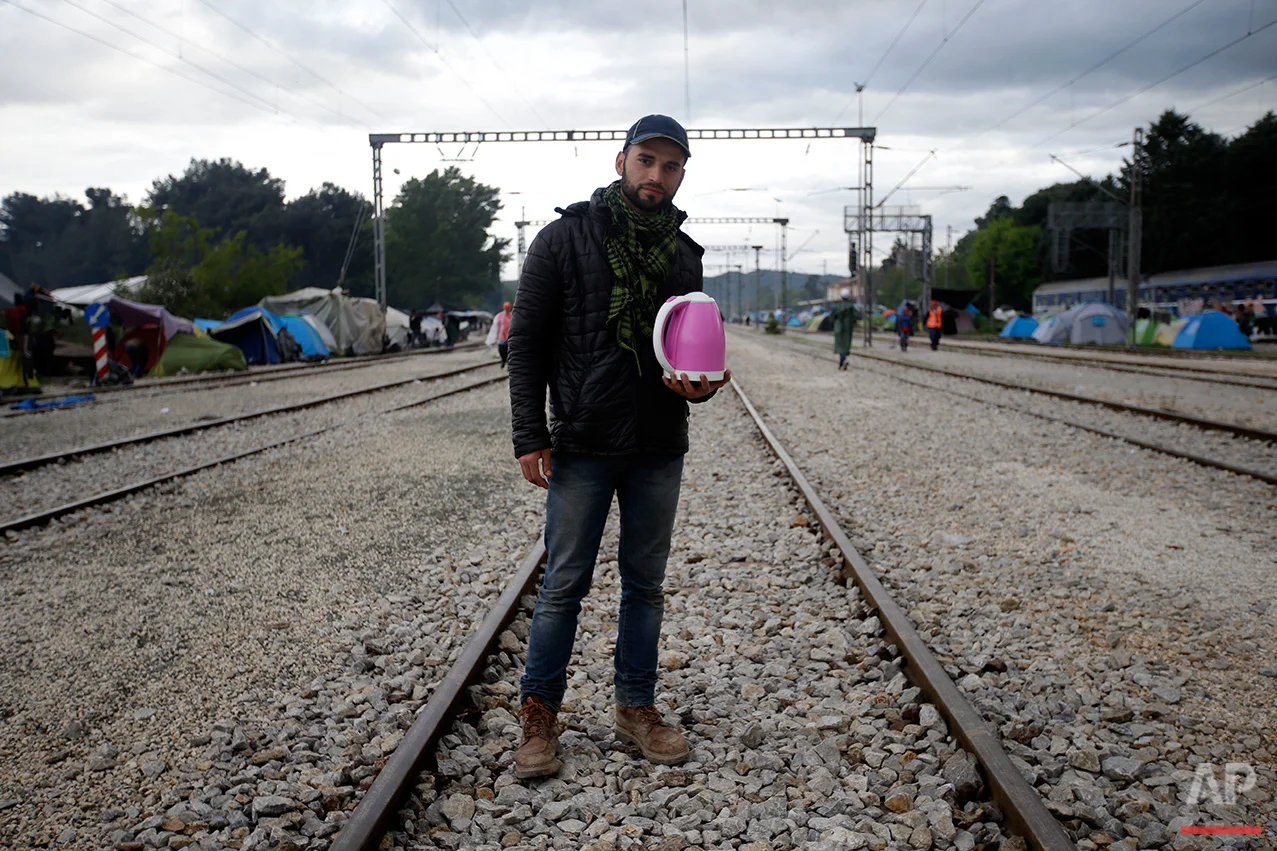 Musab Lalo, from Syria, holds a tea boiler, that he use to sell tea, poses for a portrait on the tracks of a rail way station which was turned into a makeshift camp crowded by migrants and refugees at the northern Greek border point of Idomeni, Greece, Tuesday, May 3, 2016. Many thousands of migrants remain at the Greek border with Macedonia, hoping that the border crossing will reopen, allowing them to move north into central Europe. (AP Photo/Gregorio Borgia)