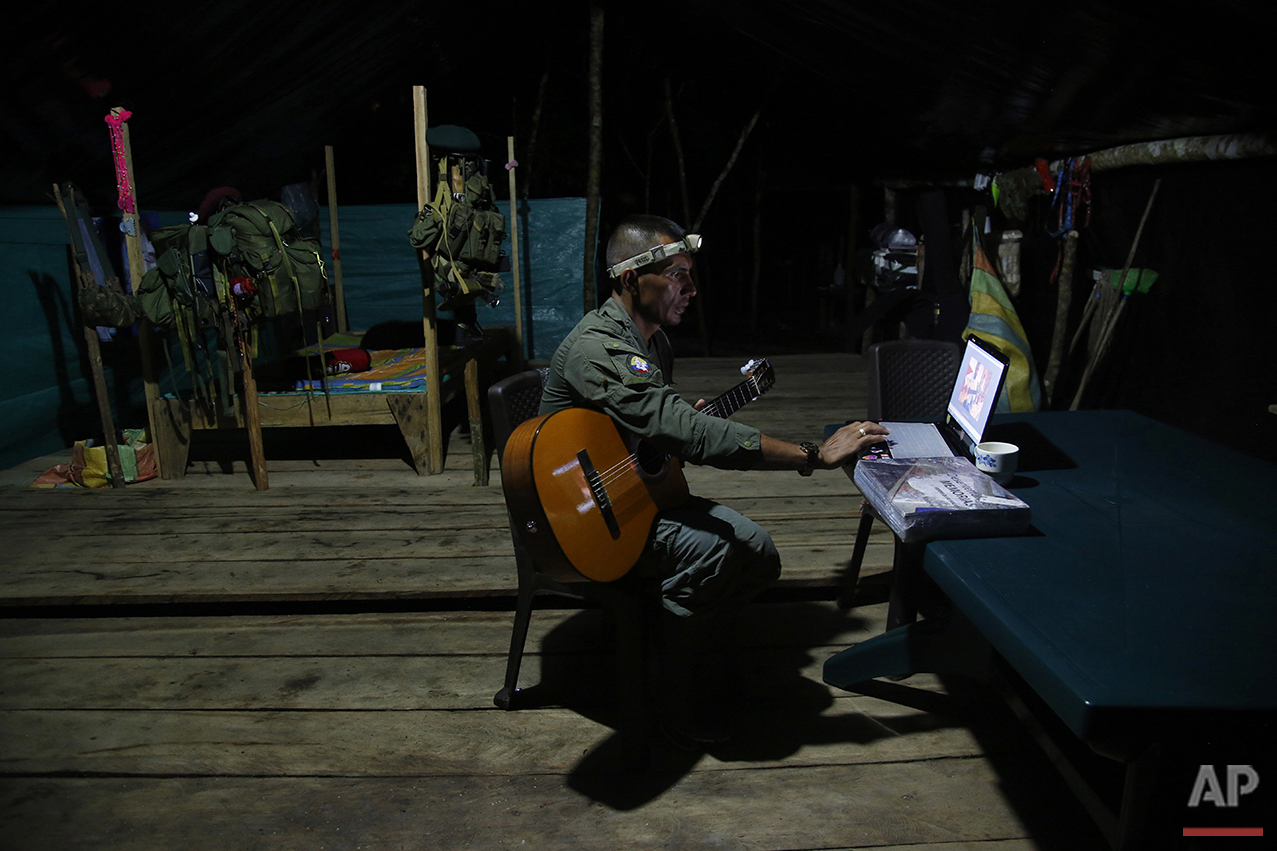  In this Aug. 11, 2016 photo, Manuel, a mid-level commander for the 48th Front of the Revolutionary Armed Forces of Colombia, or FARC, learns to play his guitar via the internet at a FARC encampment in the southern jungles of Putumayo, Colombia. The 