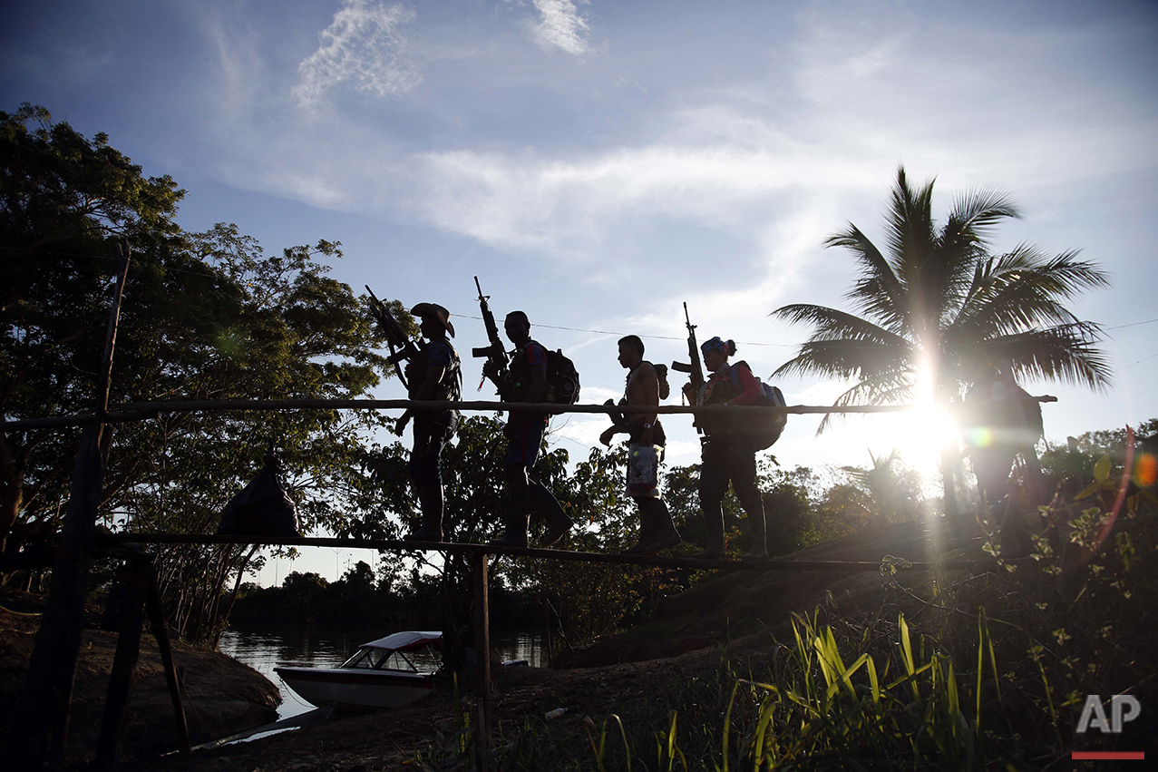  In this Aug. 11, 2016 photo, rebels of the 48th Front of the Revolutionary Armed Forces of Colombia walk on a makeshift footbridge in the southern jungles of Putumayo, Colombia. With the peace accords about to be signed between the FARC and the gove