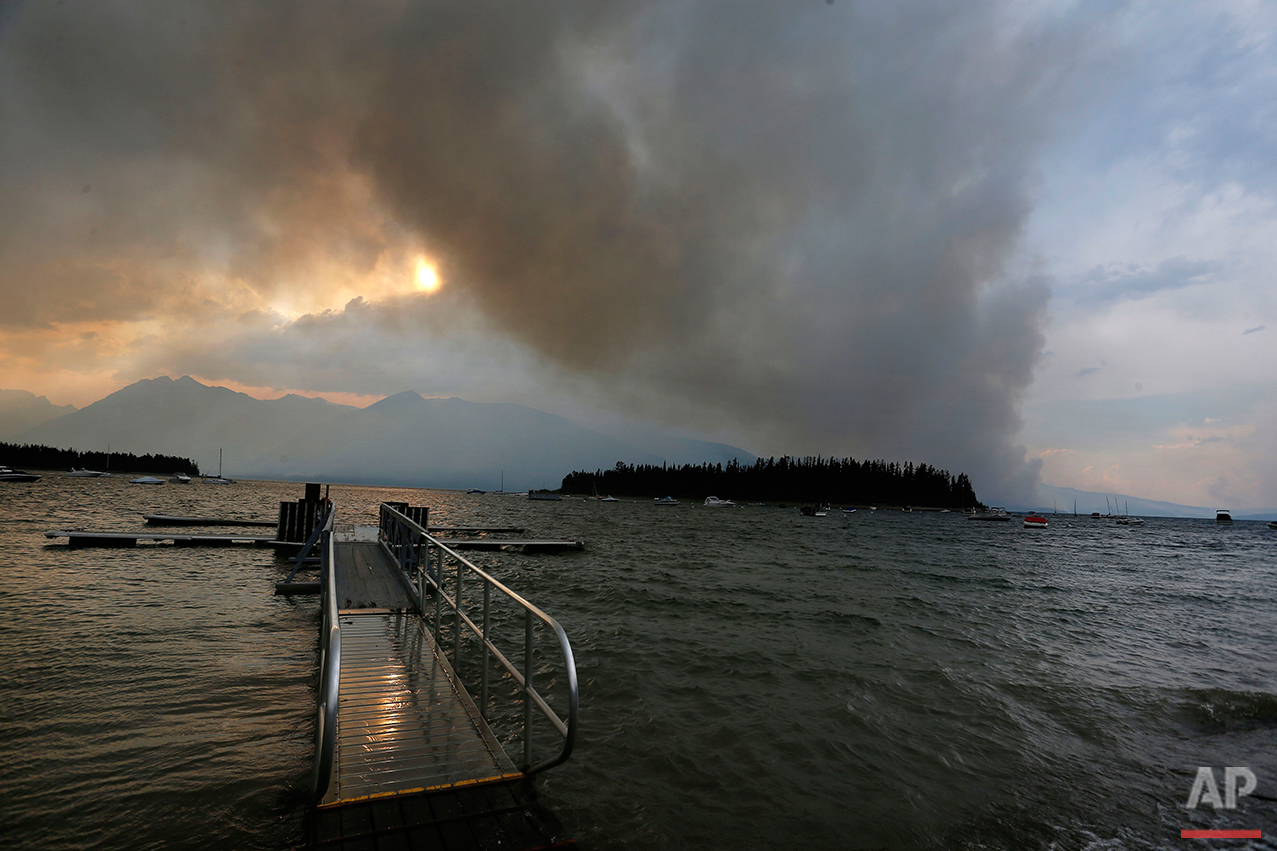  A wildfire is visible from Leek's Marina on the shore of Jackson Lake, in Grand Teton National Park, Wyo., Wednesday, Aug. 24, 2016. (AP Photo/Brennan Linsley) 