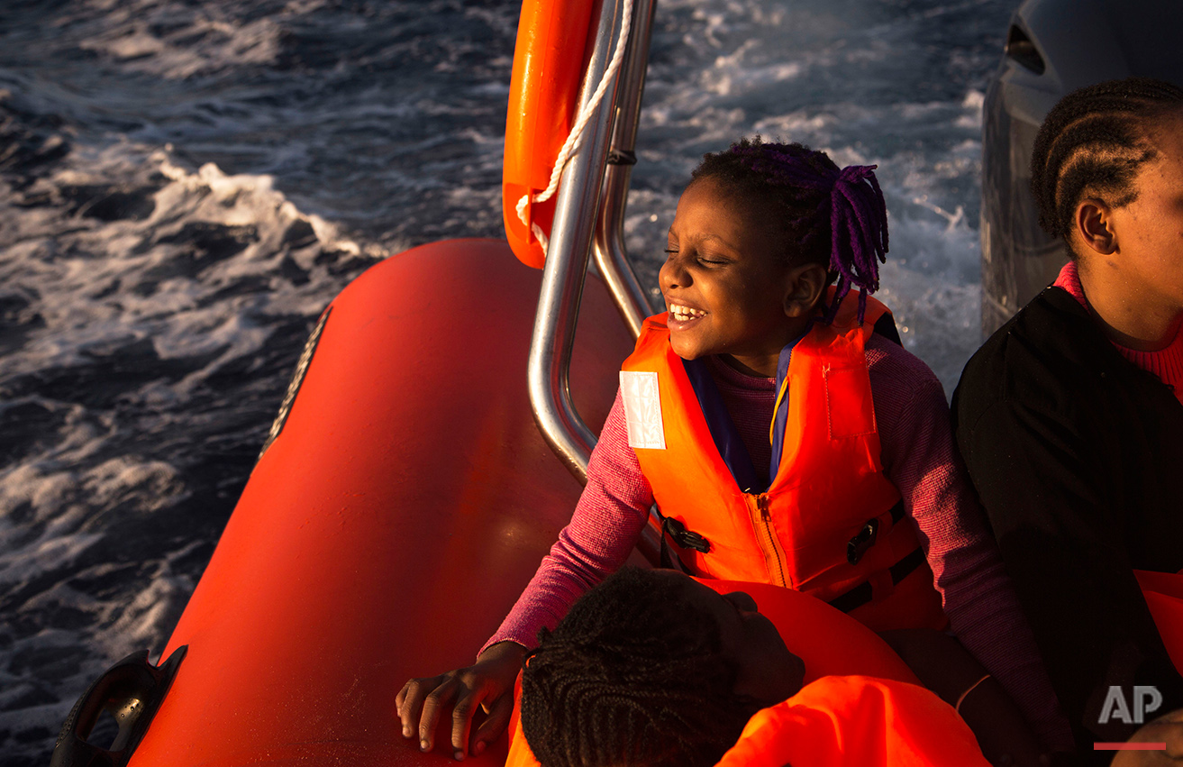  Sira, 9, a migrant from Nigeria, smiles as she rides aboard a boat of the Proactiva Open Arms NGO, after being rescued during an operation in the Mediterranean sea, about 17 miles north of Sabratah, Libya, Saturday, Aug. 20, 2016. (AP Photo/Emilio M