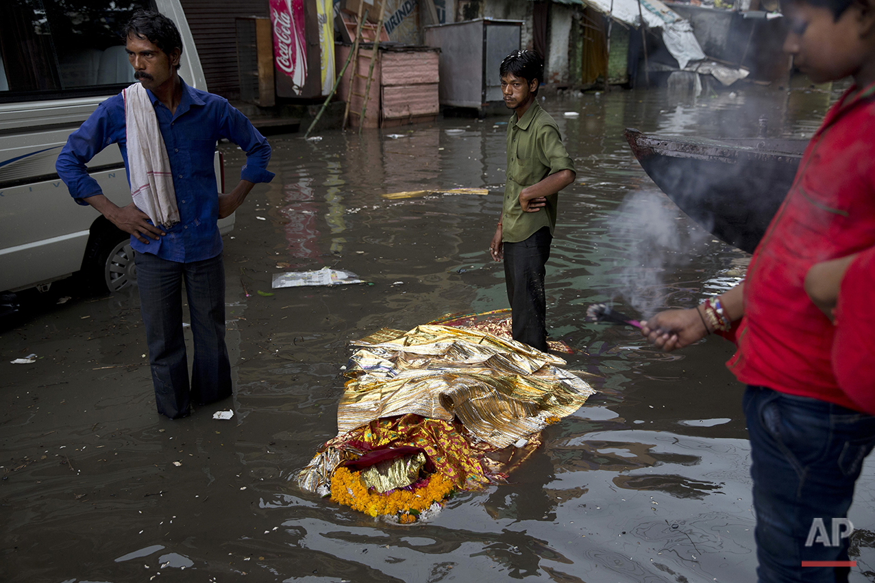  In this Friday, Aug. 26, 2016 photo, a dead body lies in a flooded street before performing a Hindu funeral at the Harishchandra Ghat in Varanasi, India. As the mighty Ganges River overflowed its banks this past week following heavy monsoon rains, l