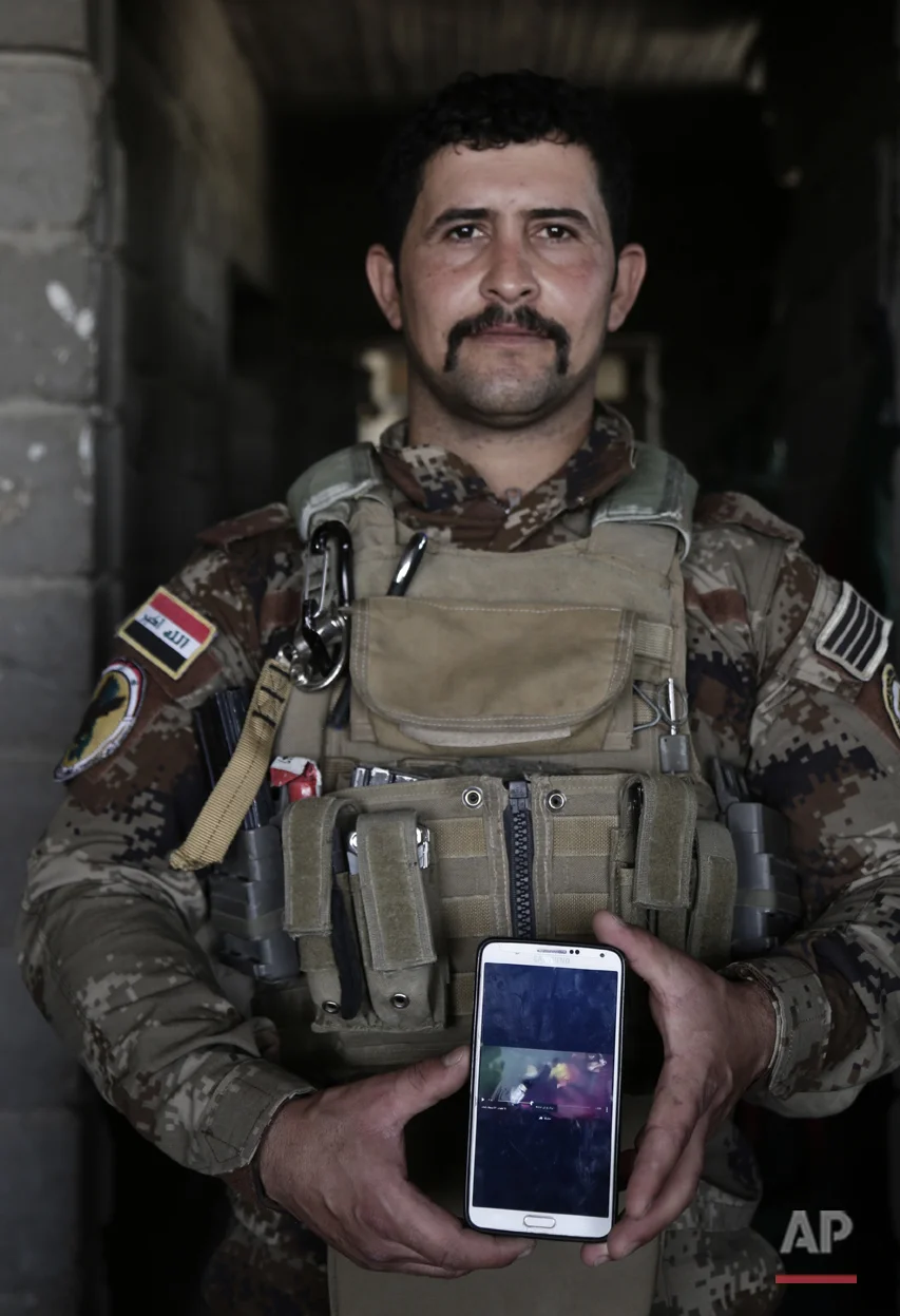  In this June 8, 2016 photo, Sgt. Ahmed Abdelaziz of Iraq's elite counterterrorism forces shows an Islamic State video of his brother's death at the hands of the IS at a battle position on the southern edge of Fallujah, Iraq. Saad Abdelaziz was kille