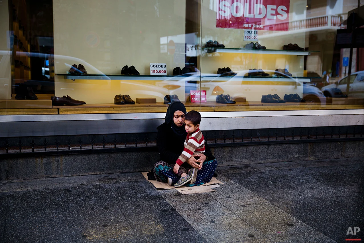  In this Tuesday, March 15, 2016 photo, a Syrian refugee woman holds her child as she begs for money on a sidewalk, in Beirut. Lebanon is home to more than 1 million registered Syrian refugees, or nearly a quarter of the country's 4.5 million people,