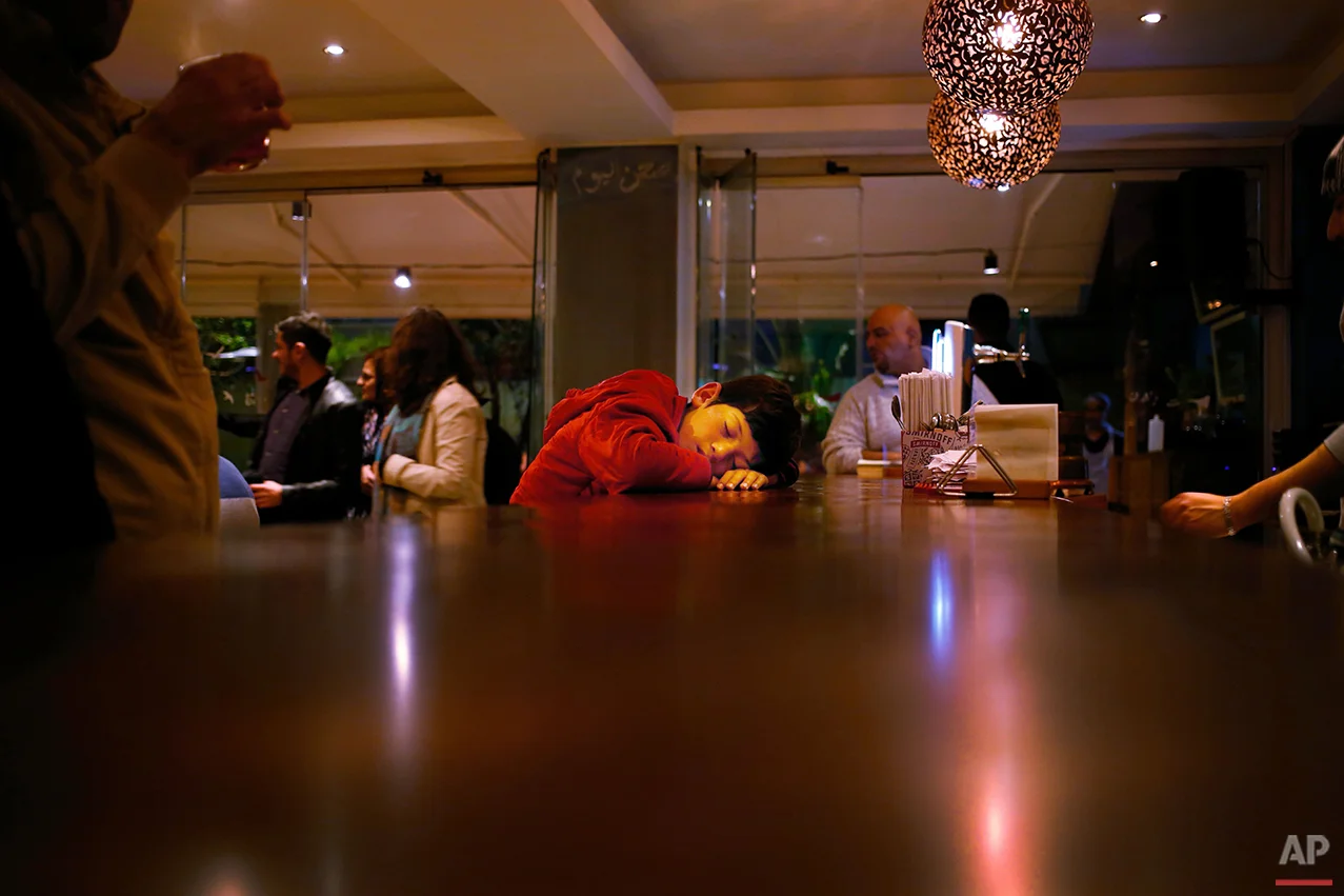  In this Tuesday, Feb. 9, 2016 photo, a Syrian refugee boy sleeps on the bar of a restaurant, after begging on the streets for hours, in Beirut. A study published last year by the International Labor Organization, UNICEF and the Save the Children cha