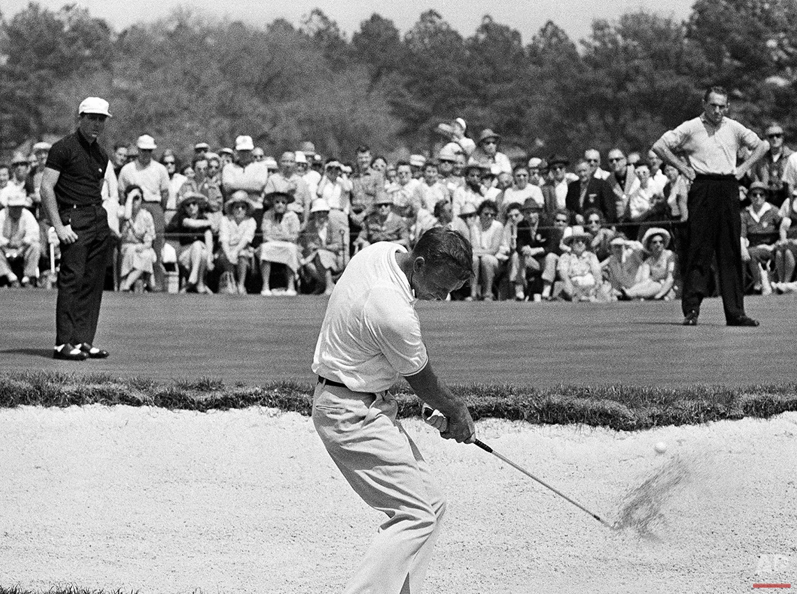 In this April 9, 1962 photo, Arnold Palmer hits from a sand trap on the second hold during a playoff in the Masters golf tournament in Augusta, Ga., as Gary Player, left, and Dow Finsterwald look on. Palmer claimed his third green jacket by winning the three-way playoff. (AP Photo/File)
