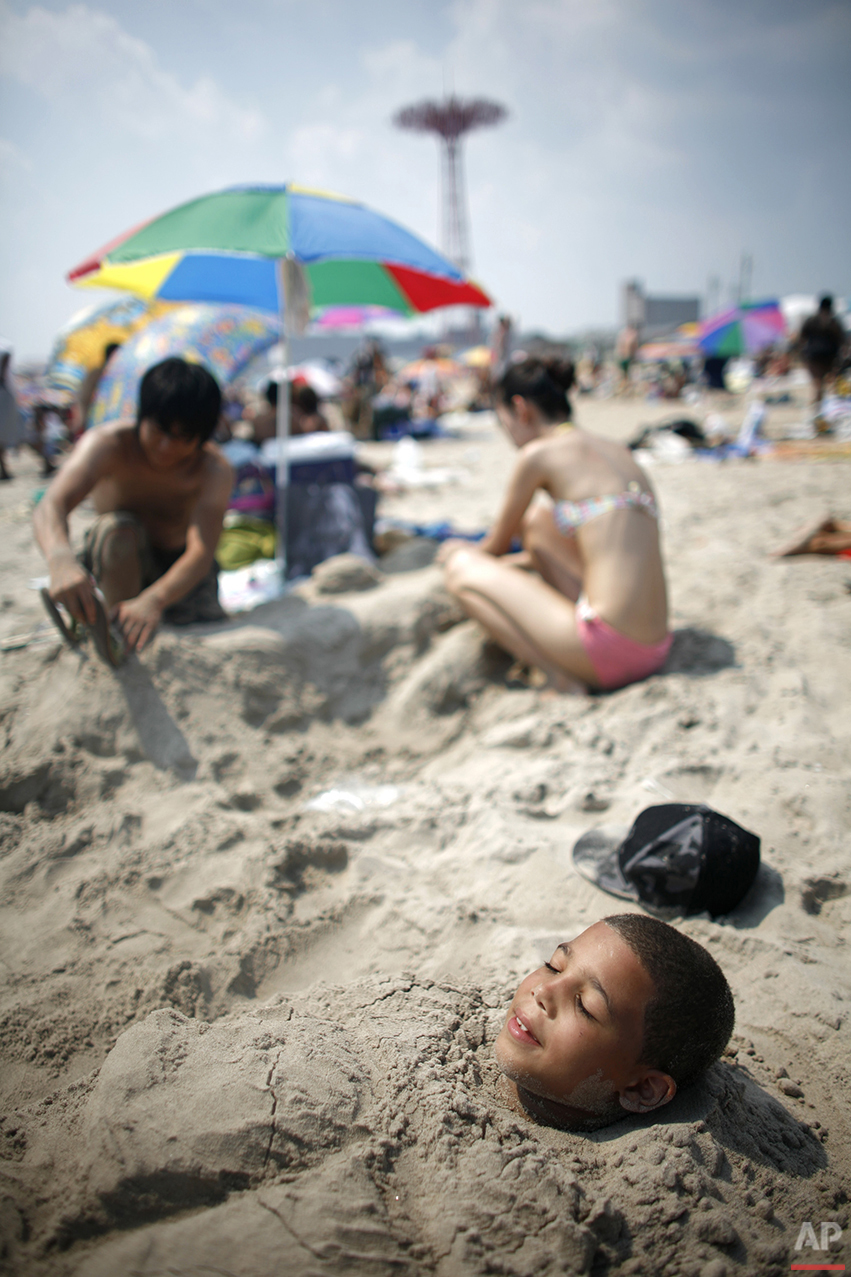  Only his face exposed to the sun, Brian Suarez, 9, stays cool by staying underground on the beach at Coney Island Wednesday, Aug. 2, 2006 in the Brooklyn borough of New York. (AP Photo/Jason DeCrow) 