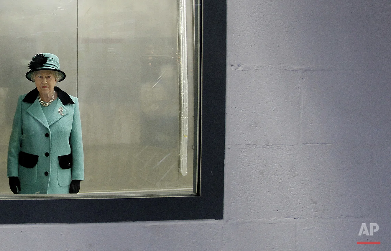 Britain's Queen Elizabeth II looks through a window, during a visit to the new Coca Cola factory, which she officially opened, in Lisburn, Northern Ireland, Friday, Oct. 22, 2010. (AP Photo/Peter Morrison)