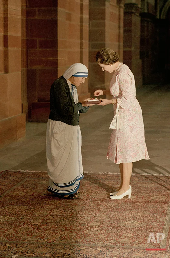 In this Thursday, Nov. 24, 1983 photo, the Queen and Mother Teresa look at the Insignia of the Honorary Order of Merit which Her majesty has just presented to the Lady of Calcutta, at the Rashtrapati Shavar, in New Delhi. Britain's Queen Elizabeth celebrates her 90th birthday on Thursday, April 21, 2016. (AP Photo)