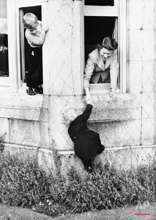 Queen Elizabeth II, right, shown playing with her two children, Prince Charles, left, and Princess Anne, climbing, at Balmoral Castle the Royal Residence on the River Dee, May 1, 1952, West Aberdeenshire, Scotland. (AP Photo)