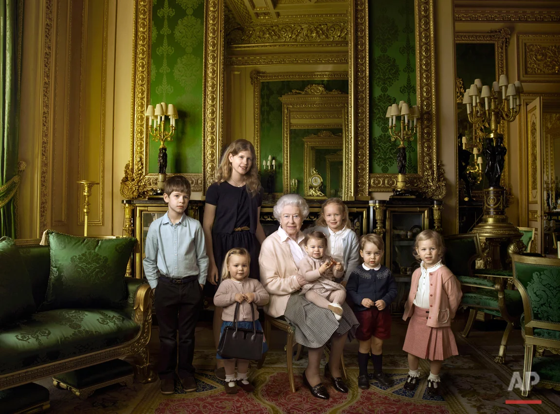 This official photograph, released by Buckingham Palace on Wednesday April 20, 2016, to mark her 90th birthday, shows Queen Elizabeth II with her five great-grandchildren and her two youngest grandchildren in the Green Drawing Room, part of Windsor Castle's semi-State apartments in Windsor England. The children are: James, Viscount Severn, 8-years-old, left, and Lady Louise, 12-years-old, second left, the children of The Earl and Countess of Wessex; Mia Tindall, holding The Queen's handbag, the two year-old-daughter of Zara and Mike Tindall; Savannah 5-years-old, third right, and Isla Phillips, 3-years-old, right, daughters of The Queen's eldest grandson Peter Phillips and his wife Autumn; Prince George, 2-years-old, second right, and in The Queen's arms and in the tradition of Royal portraiture, the youngest great-grandchild, Princess Charlotte, 11-months-old, children of Prince William and Kate Duchess of Cambridge. (© 2016 Annie Leibovitz via AP) 
