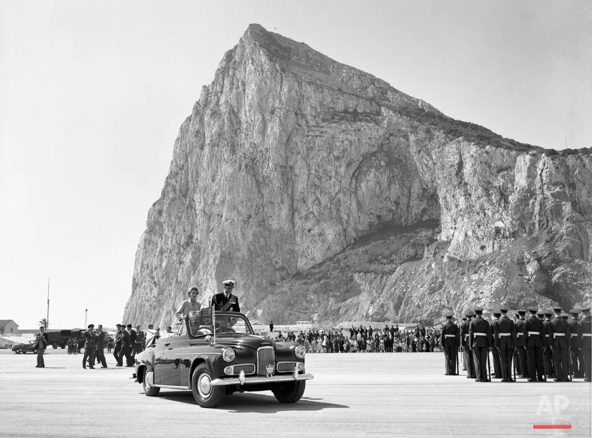 The Rock towers over Britain's Queen Elizabeth II, and the Duke of Edinburgh drive past the assembled ranks of troops and lines of bombers, during a review of the services at North Front Airfield after they had arrived in Gibraltar, on May 10, 1954. (AP Photo/Worth)