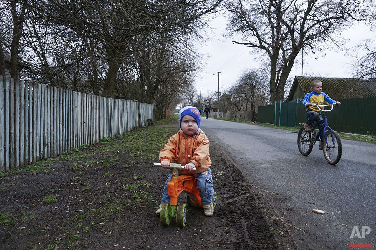  In this photo taken on Thursday, April  7, 2016, children ride bicycles in the village of Pysky, Ukraine. After the April 26, 1986 explosion and fire spewed radioactive fallout over much of Ukraine, the most heavily affected areas were classified in