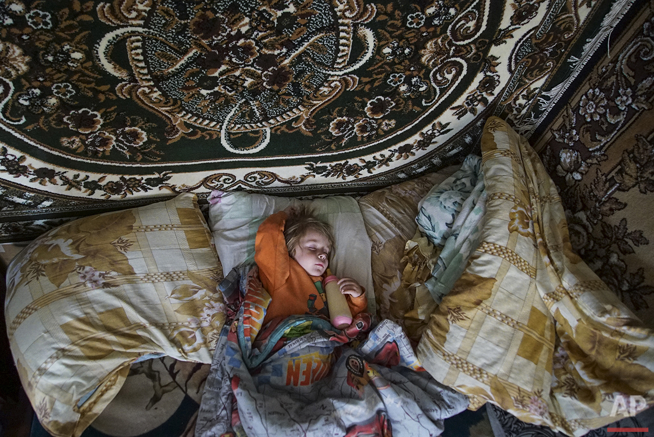  In this photo taken on Tuesday, April  5, 2016, Natalya Vetrova, one-years-old, sleeps holding a bottle with fresh cow milk at home in Zalyshany, 53 km (32 miles) southwest of the destroyed reactor of the Chernobyl plant, Ukraine. Her village is in 