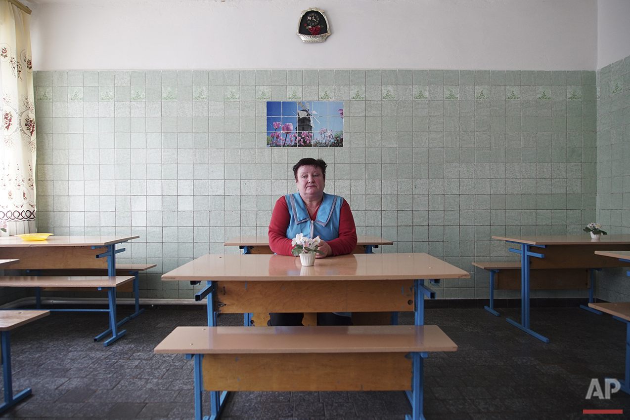  In this photo taken on Tuesday, April  5, 2016, kindergarten's cook Lyubov Shevchuk sits at the empty table of a canteen, where children used to have lunch before it was canceled, in Zalyshany, 53 km (32 miles) southwest of the destroyed reactor of 