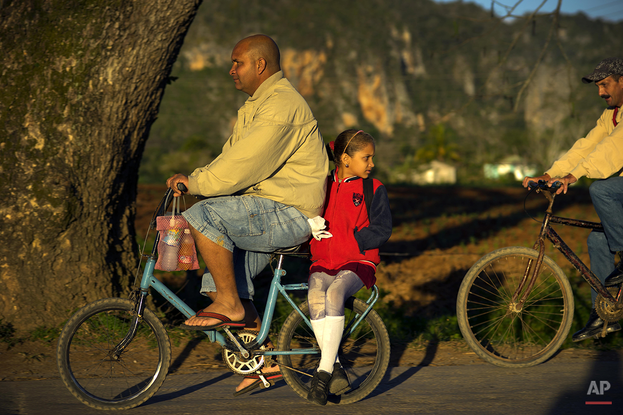  In this Feb. 26, 2016 photo, a man gives a girl a ride to school on the back of his bicycle in Vinales in the province of Pinar del Rio, Cuba, where tobacco is the main crop. Despite the flood of visitors since Cuba and the U.S. reestablished relati