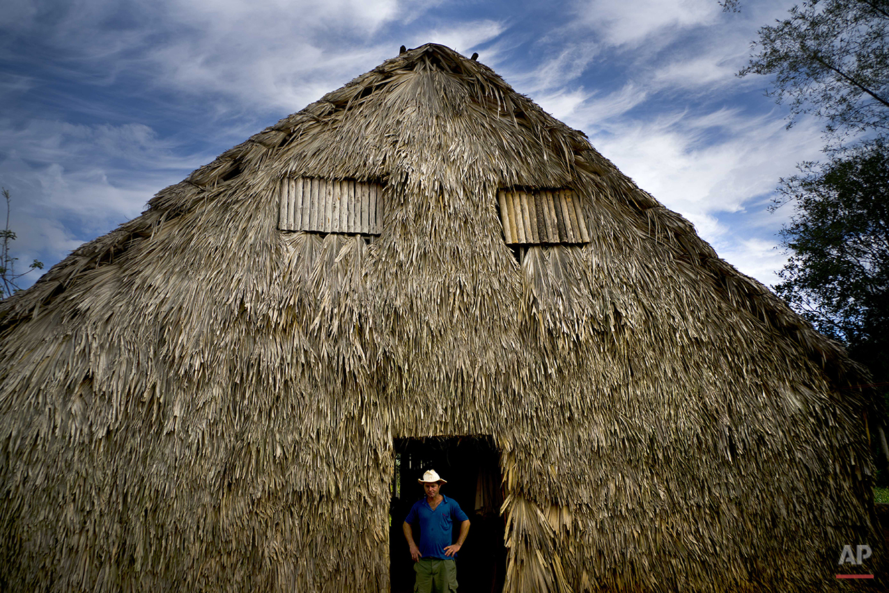  In this Feb. 27, 2016 photo, Yoberlan Castillo Garcia, 30, poses for a portrait in the doorway of the barn where tobacco leaves are dried on his family's farm in Vinales in the province of Pinar del Rio, Cuba. The barn, made of dried palm leaves and