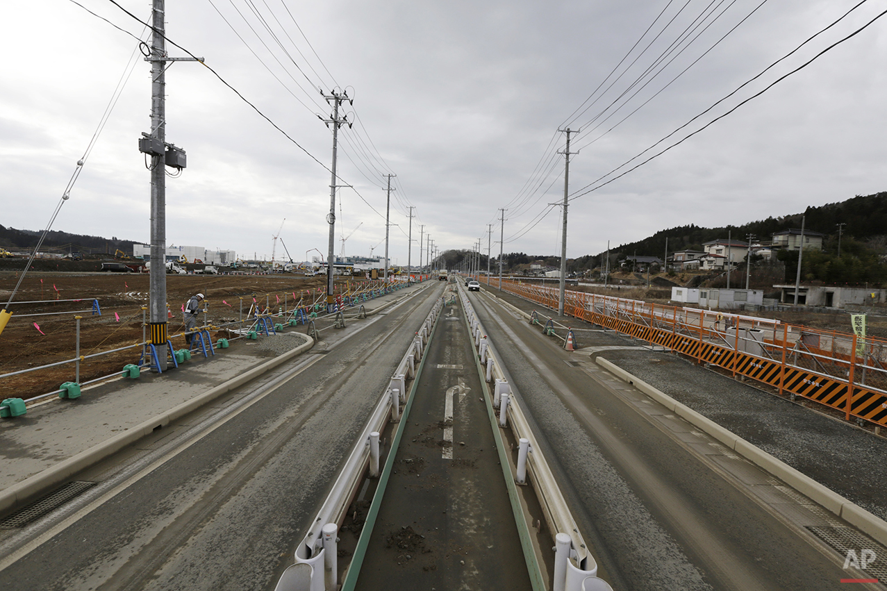  In this Monday, March 7, 2016 photo, a worker checks the construction site in Kesennuma, Miyagi Prefecture, northeastern Japan. Five years after the disaster, construction work is clearly underway but far from done. Rebuilt roads stretch to the hori