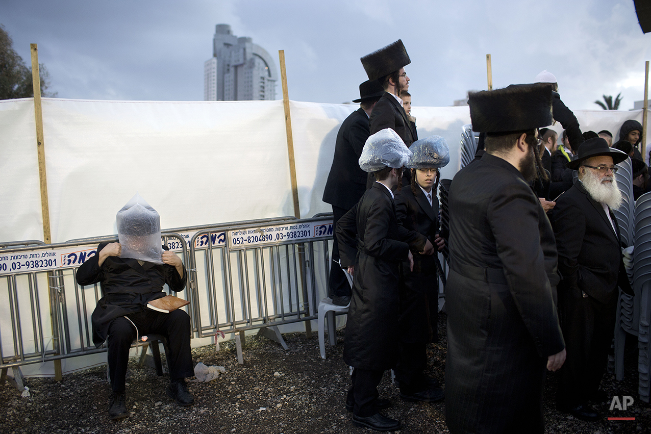  An Ultra-Orthodox Jewish man covers his hat with a plastic bag to avoid rain during the wedding of the grandson of the Rabbi of the Tzanz Hasidic dynasty community, in Netanya, Israel, Tuesday, March 15, 2016. (AP Photo/Oded Balilty) 