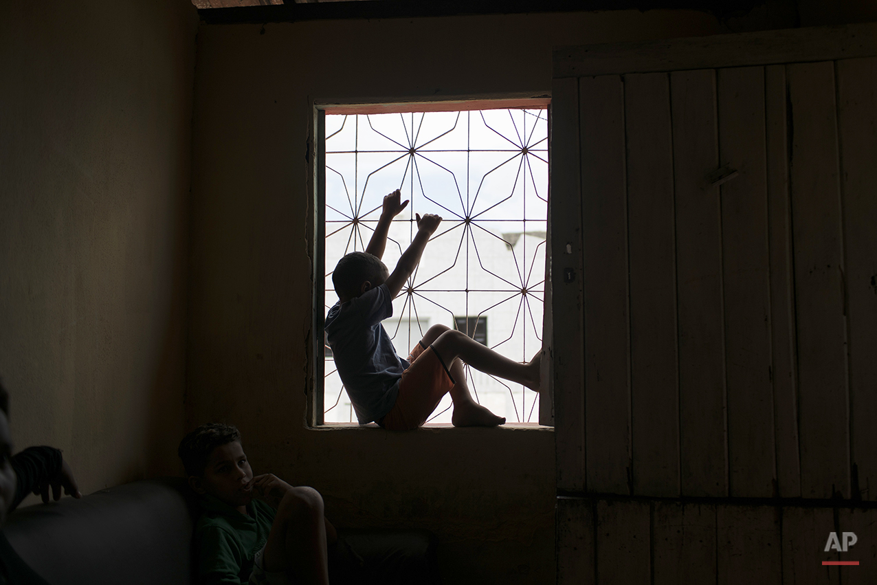  In this Jan. 30, 2016 photo, Jose Wesley's older brother Elenilson plays inside of their house in Bonito, Pernambuco state, Brazil. His mother Solange Ferreira cried when she said she had realized that her youngest son Jose Wesley, who was born with