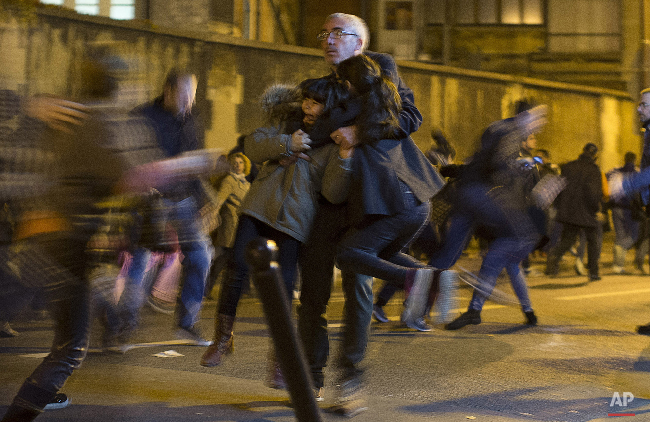  A man carries two children after panic broke out among mourners who payed their respect at the attack sites at restaurant Le Petit Cambodge (Little Cambodia) and the Carillon Hotel in Paris, Sunday, Nov. 15, 2015. Panic broke out as the crowd heard 