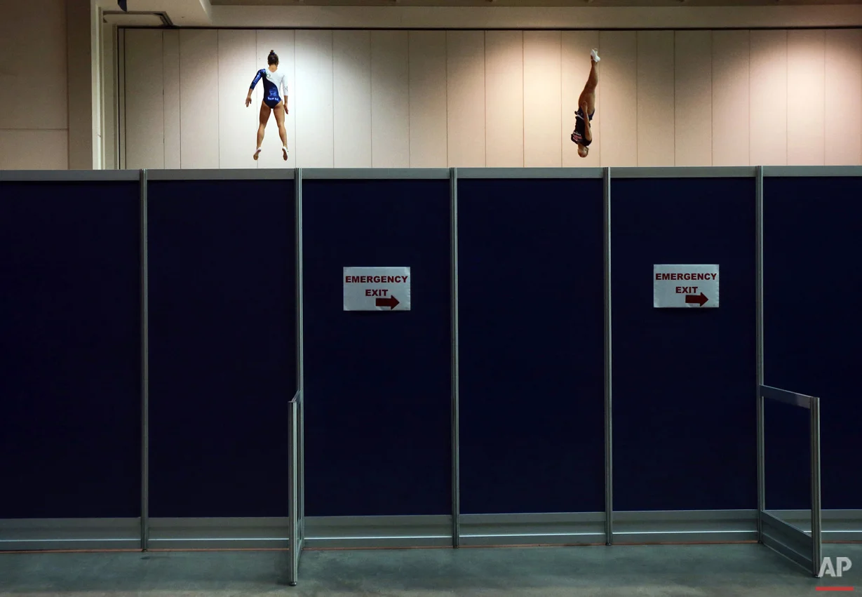 Brazil's Camilla Lopes, left, and the United States' Charlotte Drury warm up on trampolines behind a partition before women's trampoline competition at the Pan Am Games in Toronto, Sunday, July 19, 2015.