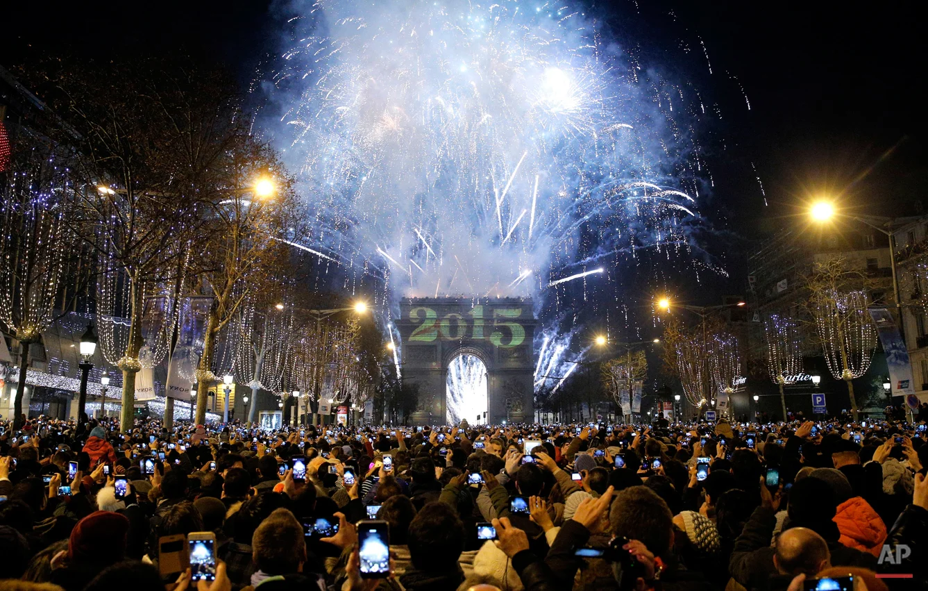 Revellers photograph fireworks over the Arc de Triomphe as they celebrate the New Year on the Champs Elysees avenue in Paris, France, Thursday, Jan. 1, 2015. (AP Photo/Christophe Ena)